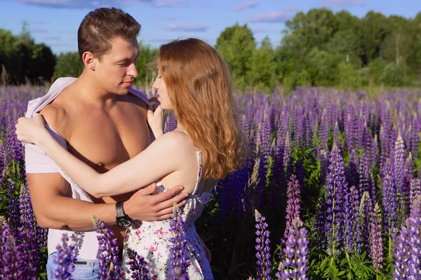 Una joven pareja hermosa abraza por la mañana en un campo floreciente brillante —  Fotos de Stock