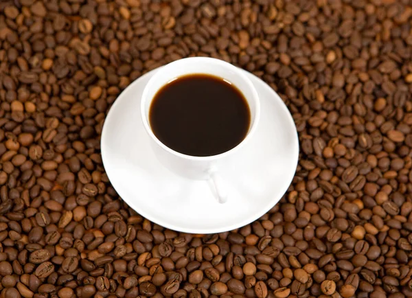 Schwarze geröstete Arabica-Kaffeebohnen und eine Tasse voll Kaffee — Stockfoto