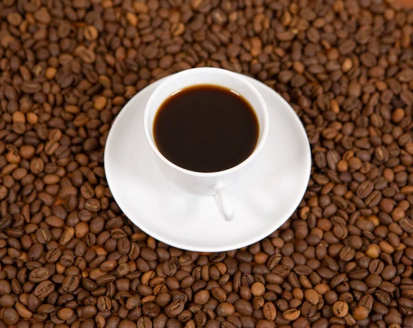 Una taza de café perfumado en una alfombra de granos de café — Foto de Stock