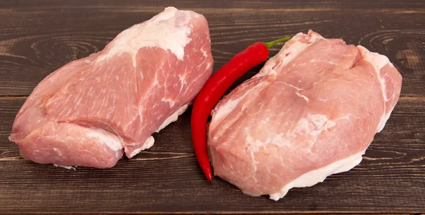 Filetes de carne jugosos crudos con pimiento rojo, listos para freír sobre un fondo de madera. —  Fotos de Stock