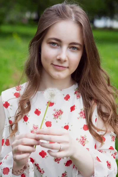 Молодая женщина восхищается одуванчиком — стоковое фото