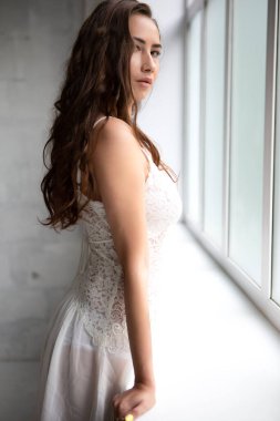 Camın önünde iç çamaşırlı, ince, seksi bir kadın duruyor.