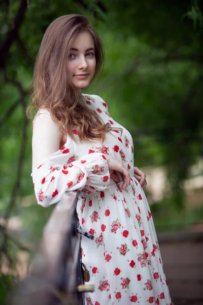 Beyaz elbiseli genç bir kadın bir şehir parkında köprüde. — Stok fotoğraf