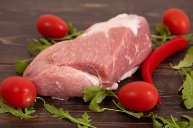 Tahta bir masada çiğ domuz eti ve sebzeler.