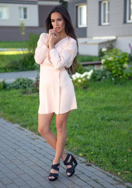 Şehir caddesinde kısa bir elbiseyle poz veren çekici esmer kadın.