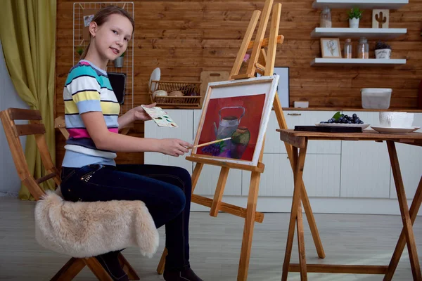 Egy fiatal lány művész festi a képet ül egy állvány a stúdióban — Stock Fotó