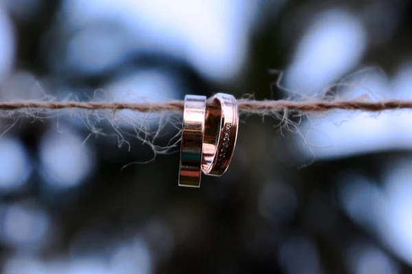 Δύο Χρυσά Γαμήλια Δαχτυλίδια Κρέμεται Από Ένα Σκοινί Ένα Φόντο — Φωτογραφία Αρχείου