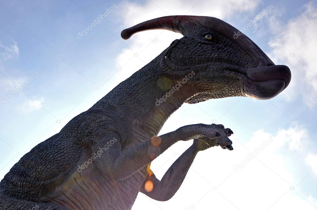 Dinosaur Parasaurolophus against a blue sky with clouds