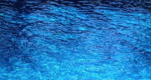 A superfície da água da piscina cor turquesa, iluminada pelo sol — Fotografia de Stock