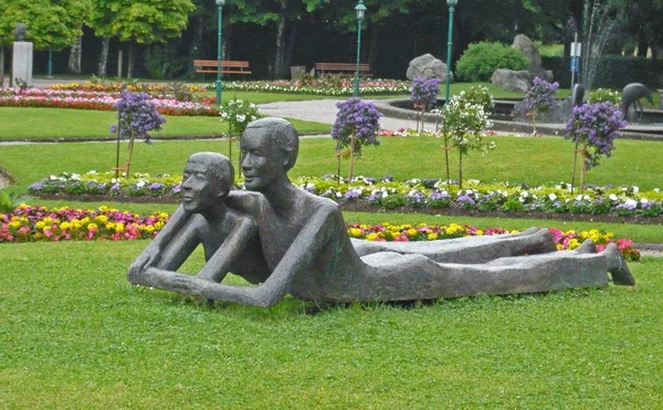 6. Juni 2011, Österreich, Wolfgangsee: Skulpturengruppe mit zwei Männern, einem Mann und einer Frau, die Seite an Seite im Gras liegen — Stockfoto