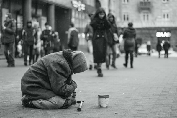 The girl gives money to an elderly beggar on a city street. Beggars. Social issue. Black and white