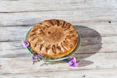 Tahta kırsal masada çiçekli bir parça elmalı turta.