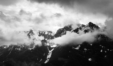 Bulutlar tarafından kapalı karlı bir dağ aralığının tek renkli.