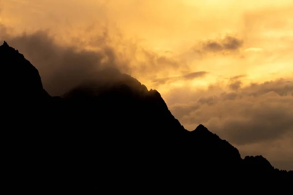 Una Silueta Una Cima Montaña Atardecer Con Nubes Circundantes —  Fotos de Stock