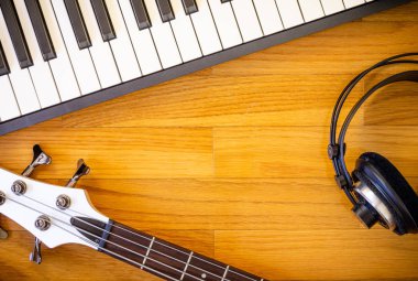 Ahşap arka plan müzik aletleri bir klavye, bas gitar ve kulaklıklar bir çift oluşan bir dizi.