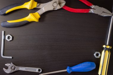 Siyah bir ahşap arka plan çeşitli donanım araçları ile: anahtarı, kesmek kerpeteni, pense, tornavida hexa anahtar, somun.