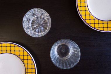 İki sarı ve beyaz tabak ve iki bardak siyah bir ahşap zemin.