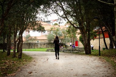 Siyah kılığına girmiş bir parkta yürüyen bir kız arkadan görünüm.