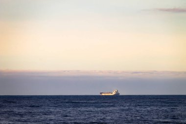 Bir kargo gemisi ufuk çizgisi, okyanusta bir mesafeden görülür.