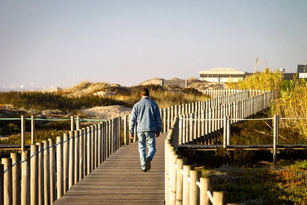 Man Walks Boardwalk Sand Ocean Denim Back View Clear Day — Stock Photo, Image