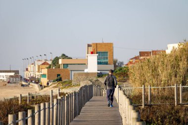 Genç adam boardwalk plaja yakın çalışır. Terli T-Shirt. Arkadan görünüm. Açık gün. Kopya alanı.