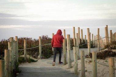 Arkadan Görünüş Doğum sözcü telefon bir aramayı cevaplama sırasında ahşap tahta yürüyüş bir kırmızı kış ceket giyen bir adamın. Kopya alanı.