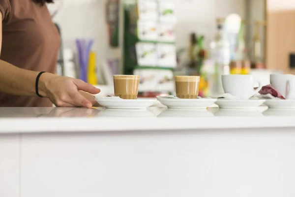 A waitress deposits two coffees in the bar of a cafeteria