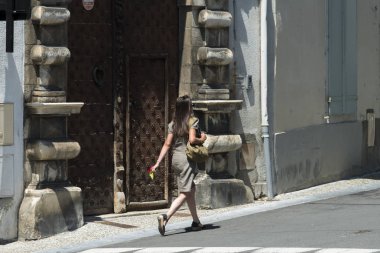 Oloron Sainte Marie - 4 Temmuz 2016: Elinde çiçek olan genç bir kız, köy sokaklarından birinde yürüyor.