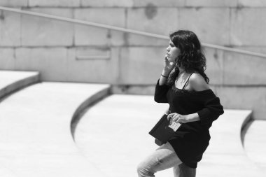 Bilbao, Ispanya-13 Temmuz 2016: Guggenheim Müzesi yakınında, onun smartphonen konuşurken genç bir kadın yürüyor.