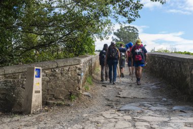 Furelos, İspanya - 31 Temmuz 2016: Sırt çantaları olan bazı genç hacılar, kırsal bir yolda yürürken, Camino de Santiago'yu yapıyor
