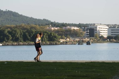Nehir kıyısındaki parkta yürüyen insanlar