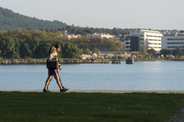 Nehir kıyısındaki parkta yürüyen insanlar