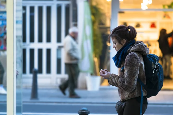 Valencia, İspanya - 24 Aralık 2016: Genç bir kız sokakta yürürken ellerini kağıt peçeteyle siliyor.