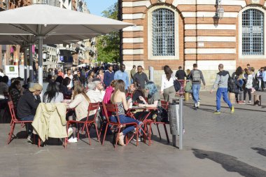 Toulouse, Fransa - 18 Nisan 2017: Bir barın terasında oturan insanlar güneşli bir bahar gününün tadını çıkarıyorlar.