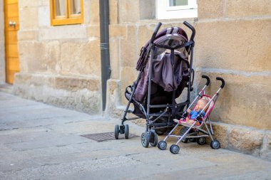 Pontevedra, İspanya - 5 Temmuz 2019 Oyuncak bebek arabasının yanında bebek arabası, sokağa park edilmiş..