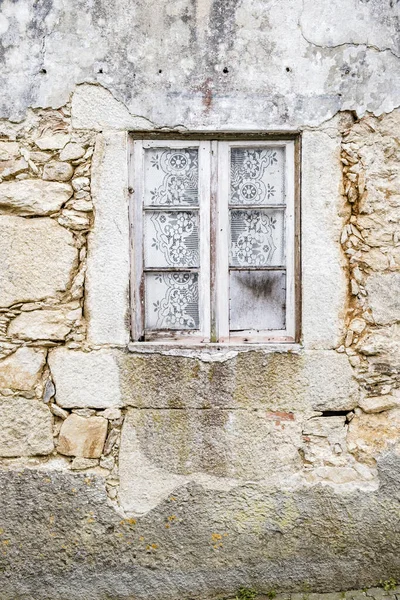 Window with curtains of a house very deteriorated by the weather in Portugal.