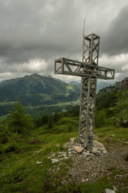 dağlar ve arka plan üzerinde bulutlu gökyüzü ile yeşil tepenin üzerinde çapraz