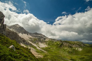 gür yeşilliklerle kaplı dağ tepe üzerinde bulutlu gökyüzü