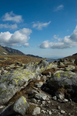 Güneş dağlık manzara mavi bulutlu gökyüzü altında ışıklı.