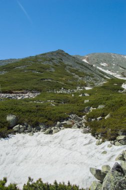 parlak güneş ışığı altında mavi gökyüzü ile dağlık manzara