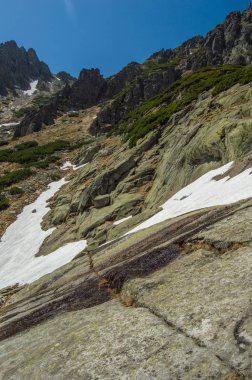 mavi gökyüzünün altında parlak güneş ışığı altında karlı tepe