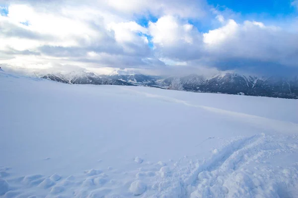 雪覆盖的山顶与遥远的山脉和多云的天空 — 图库照片