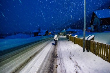 akşam karlı yolda yürüyen kadın arka görünümü