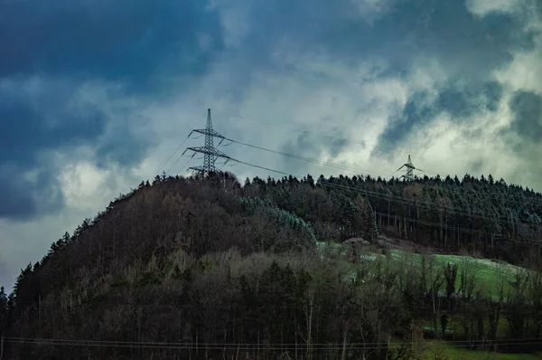 Bulutlu Gökyüzü Altında Çam Elektrik Kuleleri Ile Yeşil Tepenin Düşük — Stok fotoğraf
