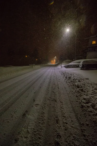 diminishing perspective view of snowcapped road illuminated at night