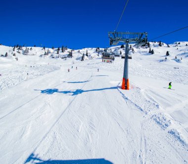 kablolu yol altında karlı yamaçta kayak insanlar