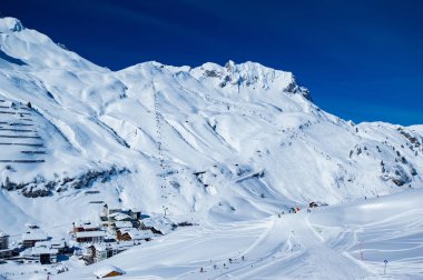 parlak güneş ışığı uzakta ki uzak insanlarla karlı kayak pisti