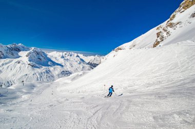 mavi gökyüzü altında kayak pistinde sürme kişi