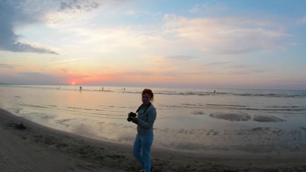 Kvinna professionell fotograf tar solnedgång foto på en ocean beach — Stockvideo