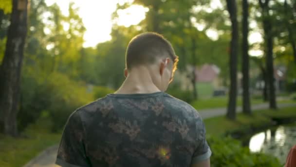 Adolescente y sus padres en un paseo por el parque en una hermosa puesta de sol luz POV disparo — Vídeo de stock